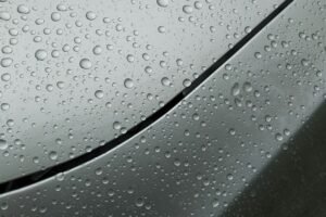 Water beads on a silver car hood after ceramic wax