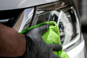 Gloved hand decontaminating white paint with a microfiber